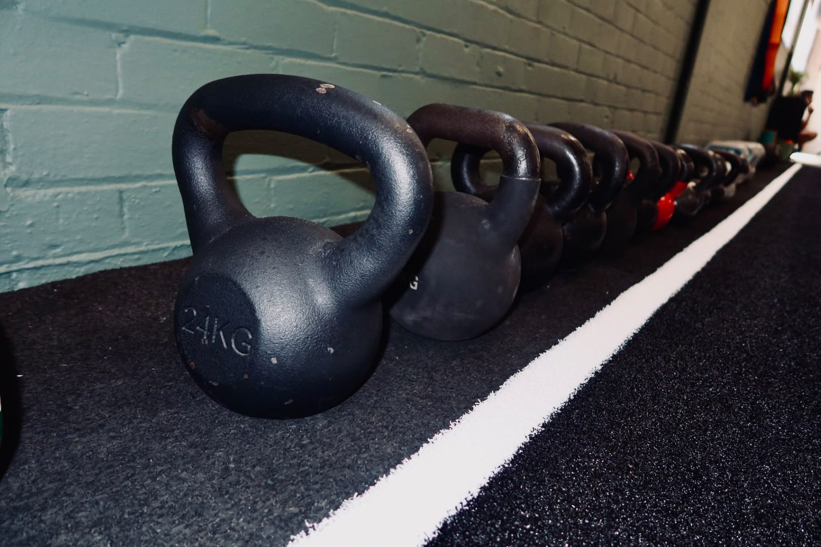 Kettlebells lined up along the wall at The PT Hut